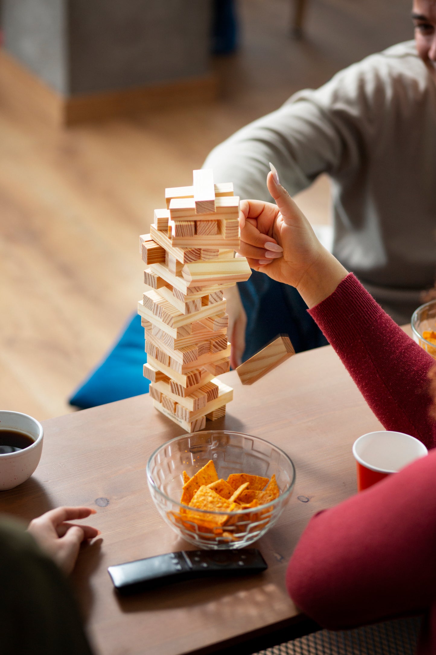 People playing Jenga at a table with snacks and drinks.