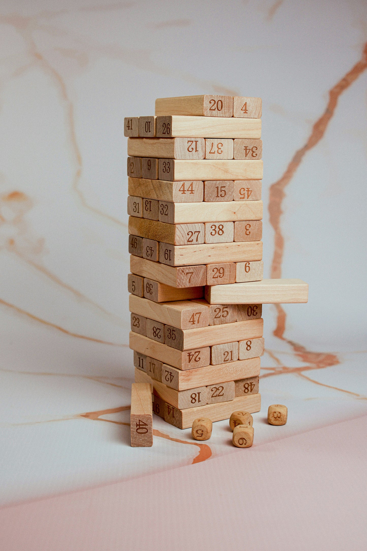 Recommended as an infographic image: a clean branded graphic showing (1) How to play in 3 steps — Build · Roll · Pull, (2) Skills developed — Numbers, Motor Skills, Strategy, Focus, (3) Who it's for — Ages 3 to adult. Alternatively, use a fun shot of the tower mid-collapse with a laughing player. The infographic version performs better on Amazon and Flipkart as it replaces the need to read bullet points for scanning buyers.