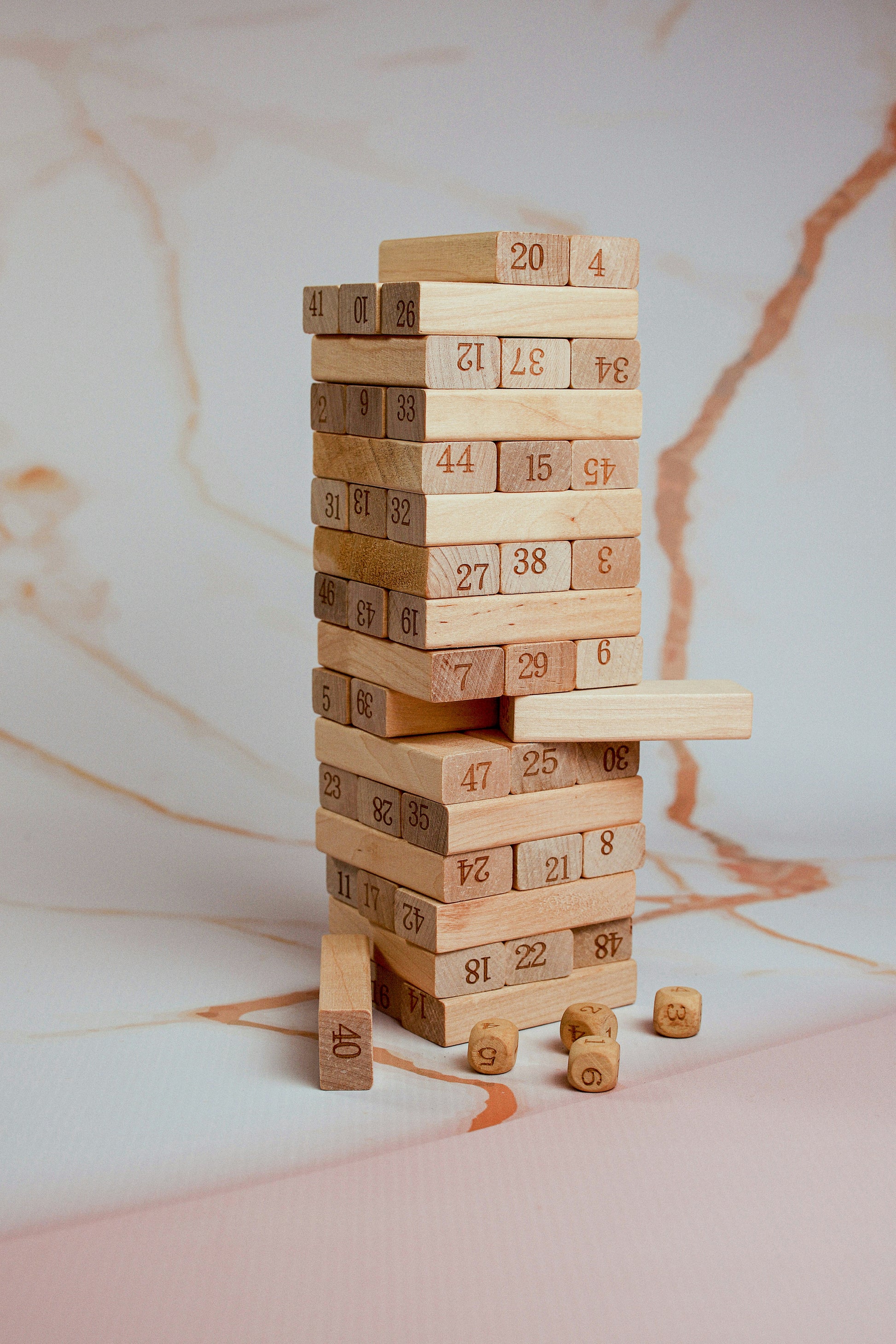 Recommended as an infographic image: a clean branded graphic showing (1) How to play in 3 steps — Build · Roll · Pull, (2) Skills developed — Numbers, Motor Skills, Strategy, Focus, (3) Who it's for — Ages 3 to adult. Alternatively, use a fun shot of the tower mid-collapse with a laughing player. The infographic version performs better on Amazon and Flipkart as it replaces the need to read bullet points for scanning buyers.